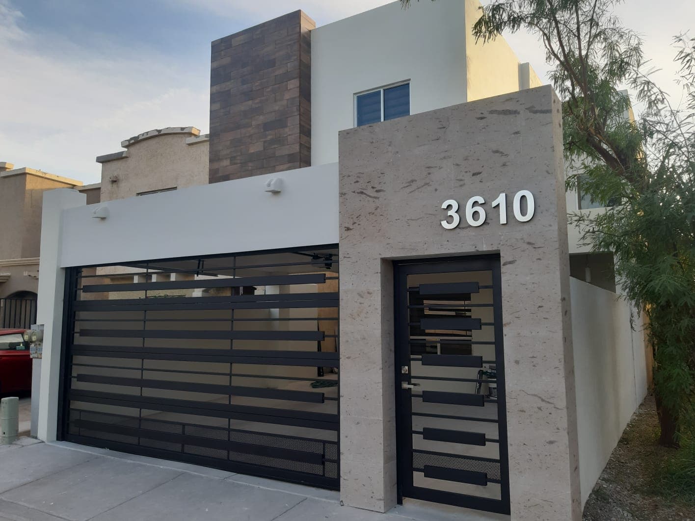 Fachada de la casa 3610 con muro de cantera y portón de herrería negra