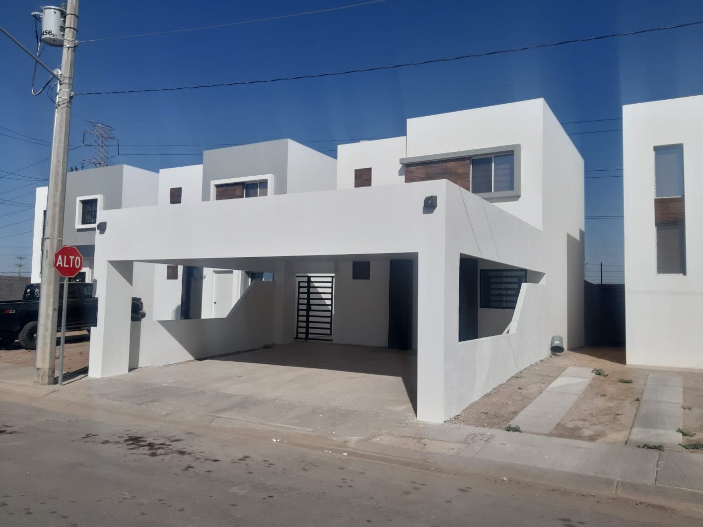 Casa blanca minimalista de esquina con cochera volada